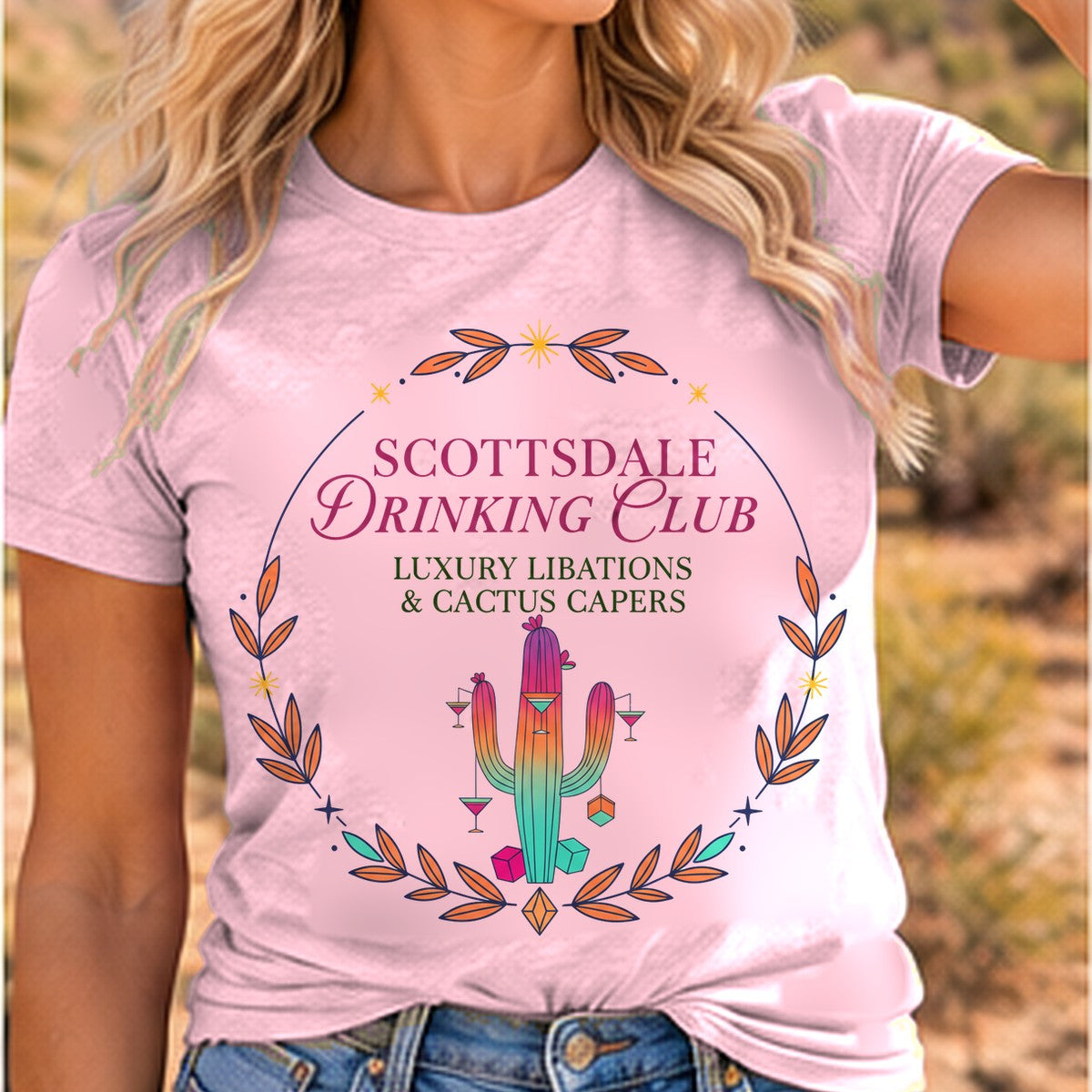 Scottsdale Drinking Club Cocktail Arizona T-shirt worn by a woman in the Arizona desert, pink tee